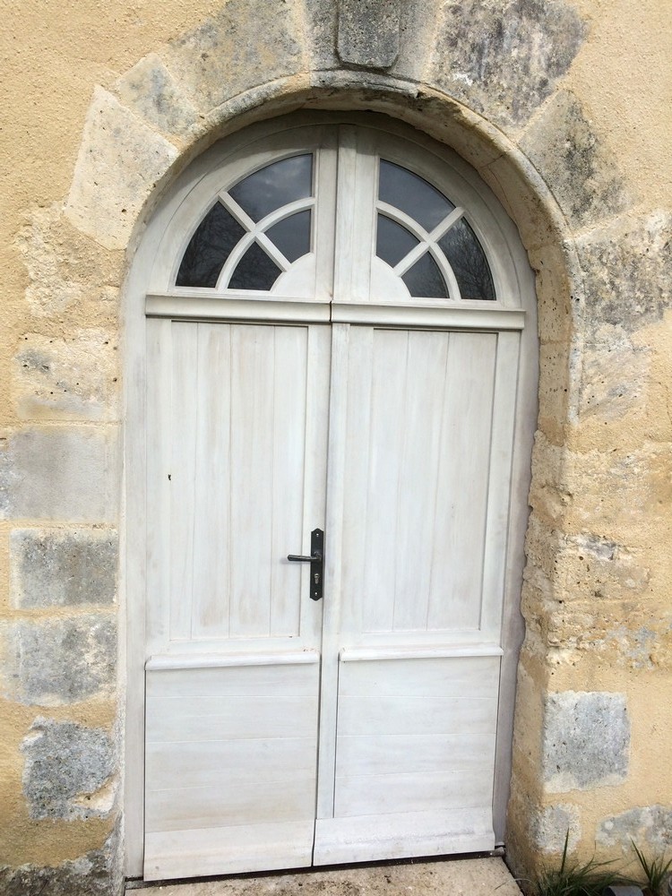 Porte d'entrée plein cintre avec fausse imposte à petits bois rayonnants et médaillon
